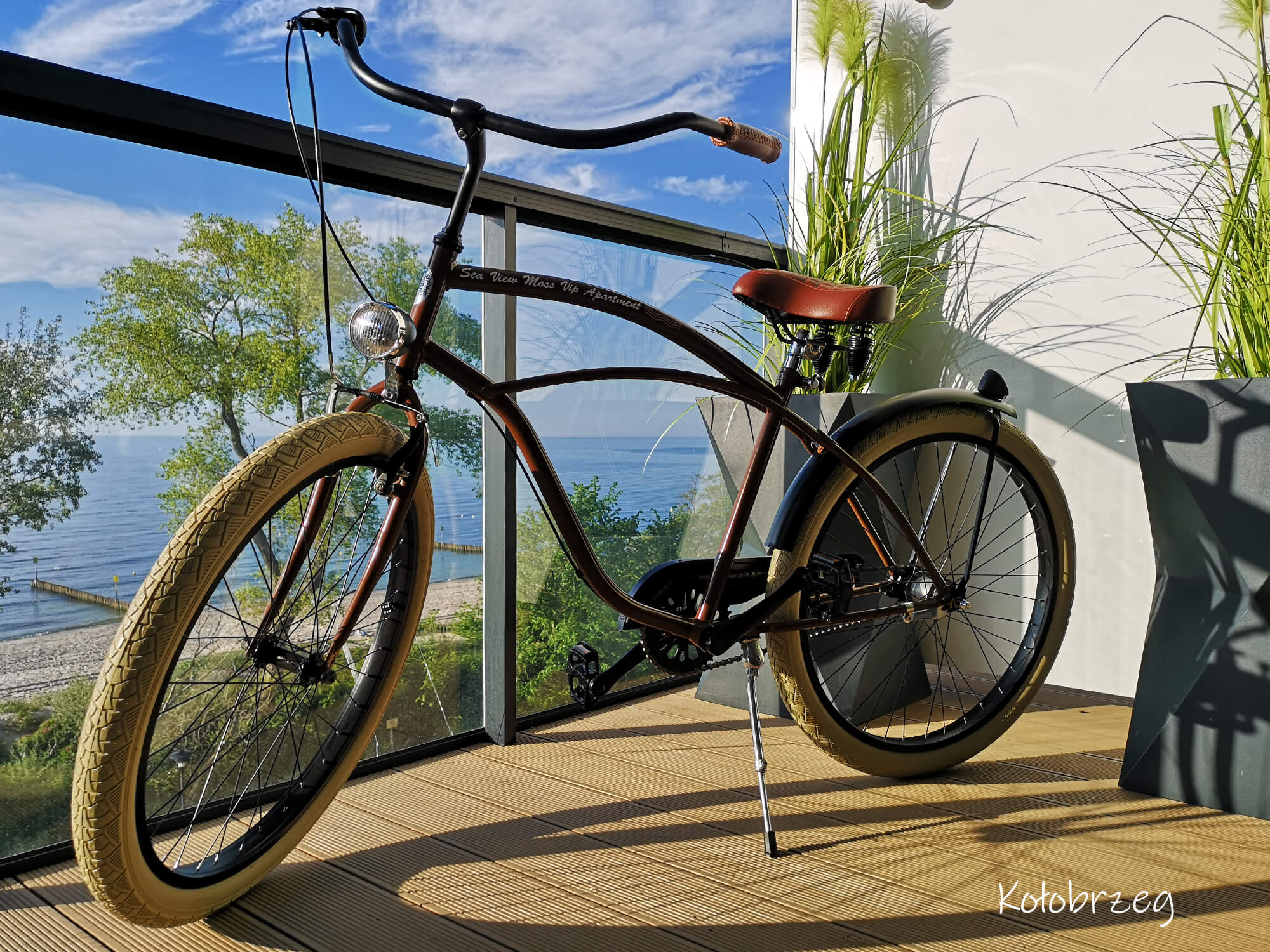 Ein stilvolles Fahrrad auf einer Terrasse mit Meerblick und dem Schriftzug „Kołobrzeg“